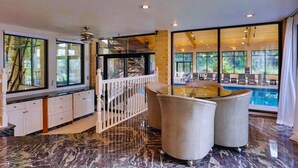 A spacious room with a marble floor, a pool view, and a modern kitchen with white cabinets. - Stien Oasis: Heated Indoor Pool Oasis With Theater, Bar&Tennis Court. (Canfield)