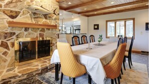 A dining area with a stone fireplace, wooden ceiling, and a large dining table with chairs. - Stien Oasis: Heated Indoor Pool Oasis With Theater, Bar&Tennis Court. (Canfield)