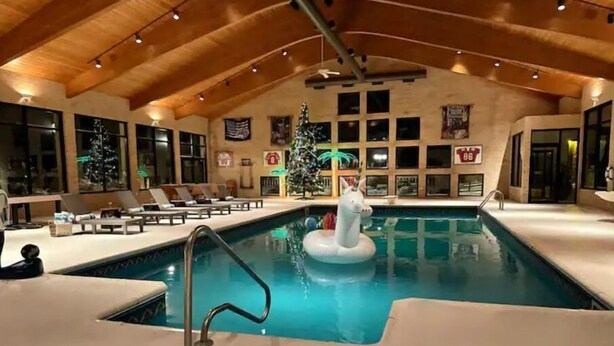 An indoor swimming pool with a white inflatable horse, lounge chairs, and a high wooden ceiling. - Stien Oasis: Heated Indoor Pool Oasis With Theater, Bar&Tennis Court. (Canfield)