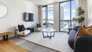 A modern living room with a sofa, a coffee table, a bench, and a TV. - Modern tranquility in the city (Auckland)