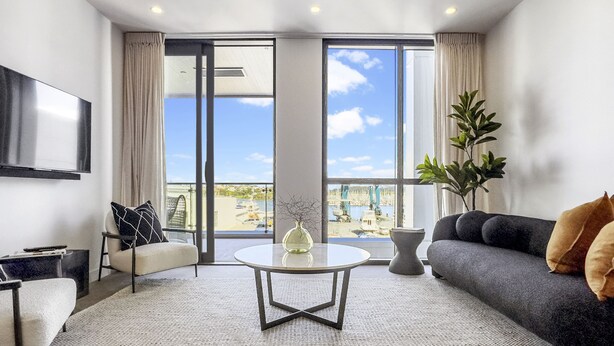 A modern living room with a sofa, a coffee table, and a TV mounted on the wall. - Modern tranquility in the city (Auckland)