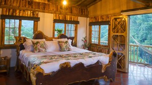 A wooden bed with a floral bedspread in a room with large windows and a balcony. - Hacienda Charrascal Coffe Farm (Manizales)