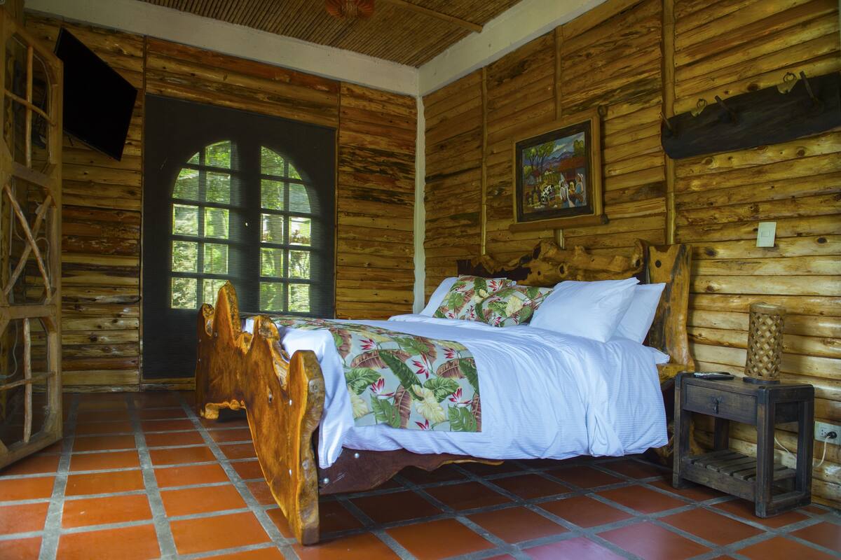 A wooden cabin room with a bed, a window, and a wooden floor.