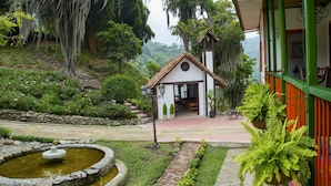 A small building with a tiled roof and a stone pathway leading to it. - Hacienda Charrascal Coffe Farm (Manizales)