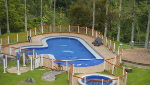 A swimming pool with a deck, surrounded by a fence, and a small circular pool within it. - Hacienda Charrascal Coffe Farm (Manizales)