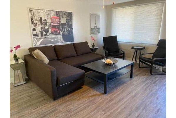 Relax in this stylish living room with a sofa, coffee table, and floor-to-ceiling window.