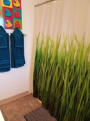 Bathroom features a shower area with a showerhead and a decorative wall mural.
