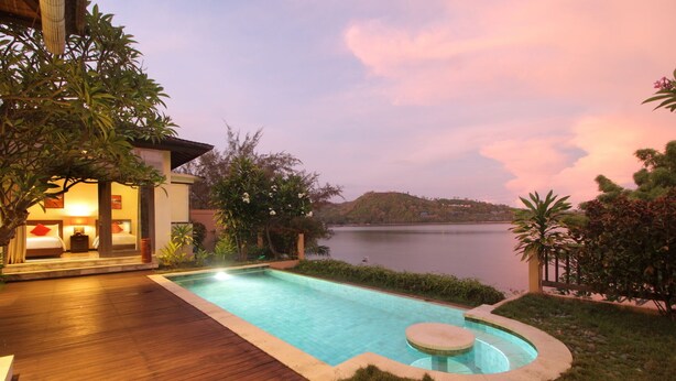 Un hôtel doté d’une piscine, d’une terrasse en bois et offrant une vue sur un lac au crépuscule.
