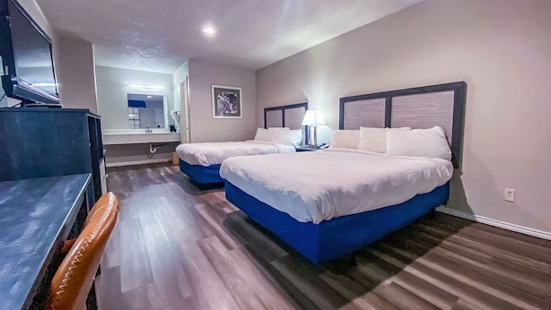 Une chambre d’hôtel avec deux lits, un bureau et une télévision.