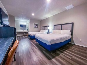 Hotellihuone, jossa on kaksi sänkyä, työpöytä ja televisio.