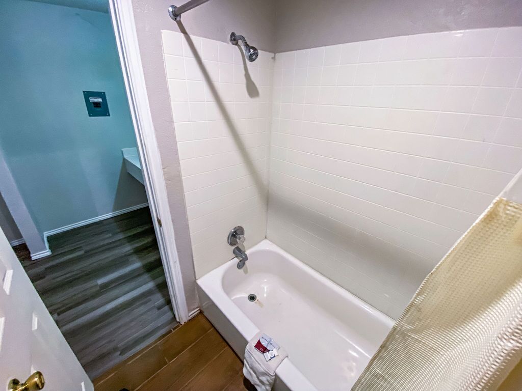 A bathroom with a white bathtub, a shower, and a tiled wall.