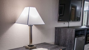 Une chambre d’hôtel équipée d’un bureau, d’une chaise, d’une lampe, d’une télévision et d’une kitchenette.