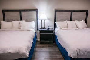Une chambre d’hôtel avec deux lits, une table de chevet avec une lampe et un téléphone.