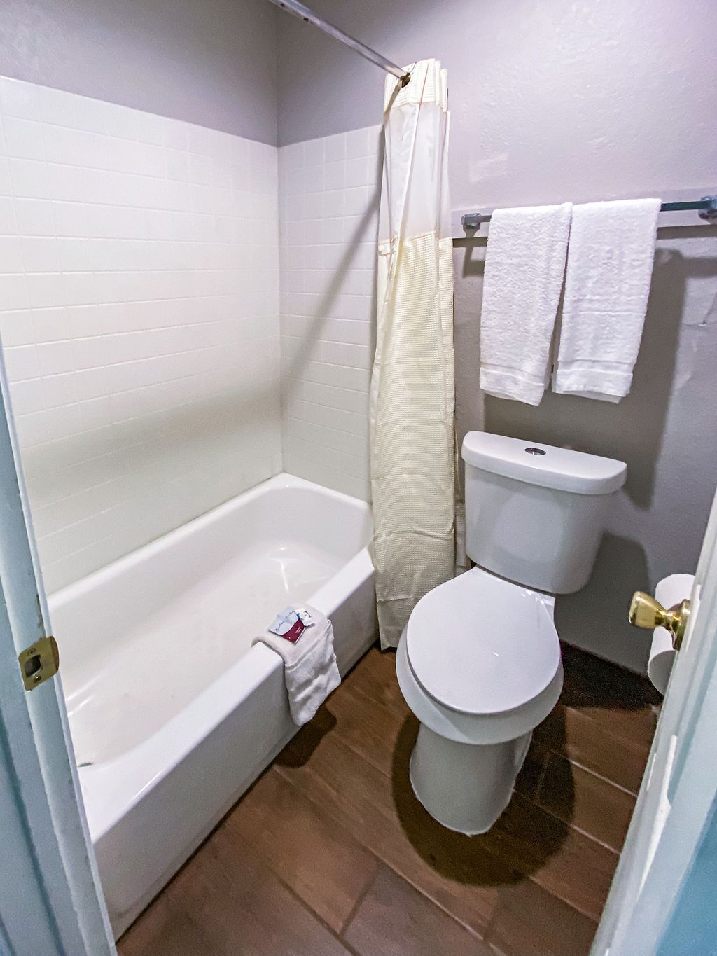 A bathroom with a bathtub, toilet, and shower curtain.