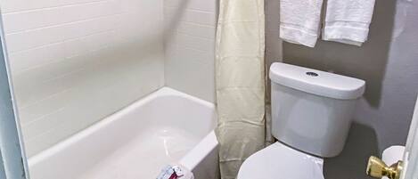 A bathroom with a bathtub, toilet, and shower curtain.