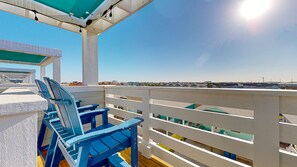 A balcony with blue chairs and a white railing, overlooking a residential area.