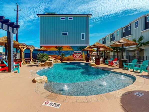 Uma área de piscina com um mural, cadeiras de descanso e um aviso contra mergulhos.
