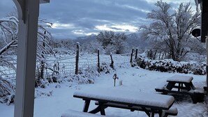 Area esterna innevata con tavoli da picnic e una zona coperta con posti a sedere.