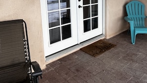 Un'area patio coperta con una porta scorrevole in vetro, un cartello di benvenuto e una poltrona Adirondack blu.