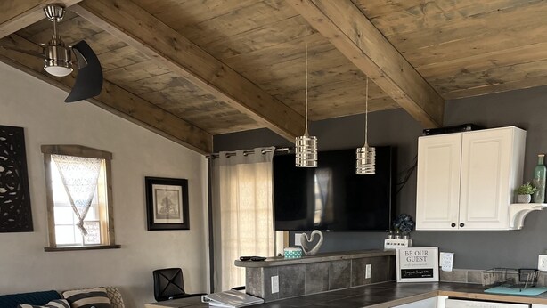 Una cucina moderna con soffitto in legno, angolo bar e zona pranzo.
