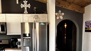 Una cucina moderna con elettrodomestici in acciaio inossidabile, mobili bianchi e soffitto in legno.