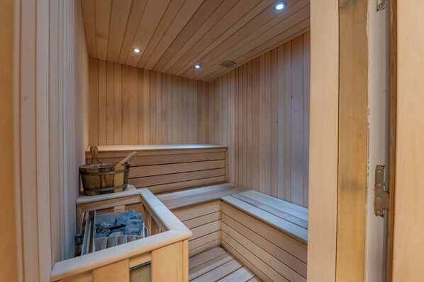 Een sauna met houten banken en een stenen bak.