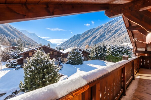 A wooden cabin with a balcony overlooking a snowy mountain landscape.