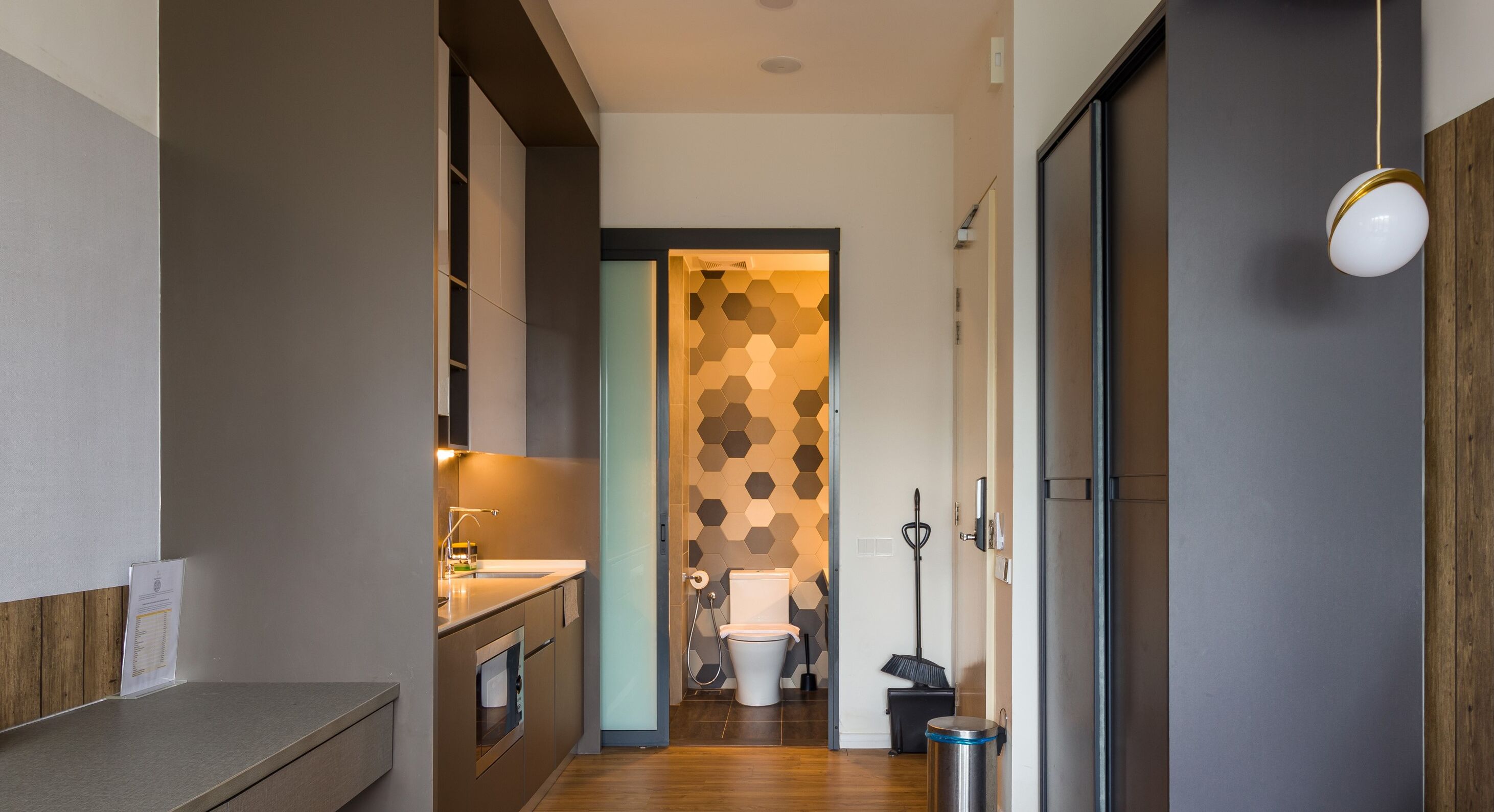 A modern bathroom with a hexagonal patterned wall, a toilet, and a trash bin.