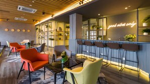 Ett modernt loungeområde med sittplatser, en bar och en neonreklamskylt.