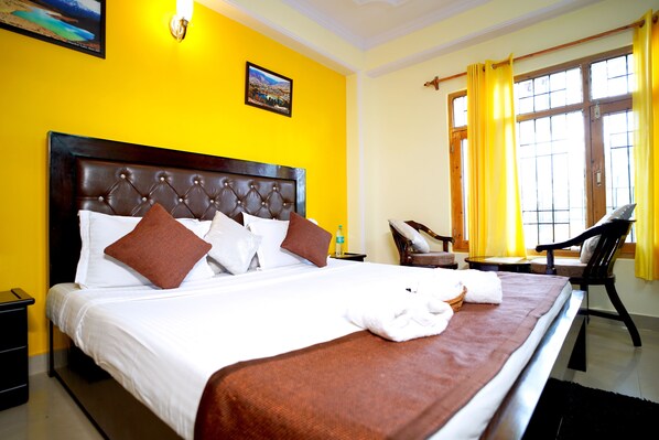 A hotel room with a large bed, a chair, and a window with curtains.