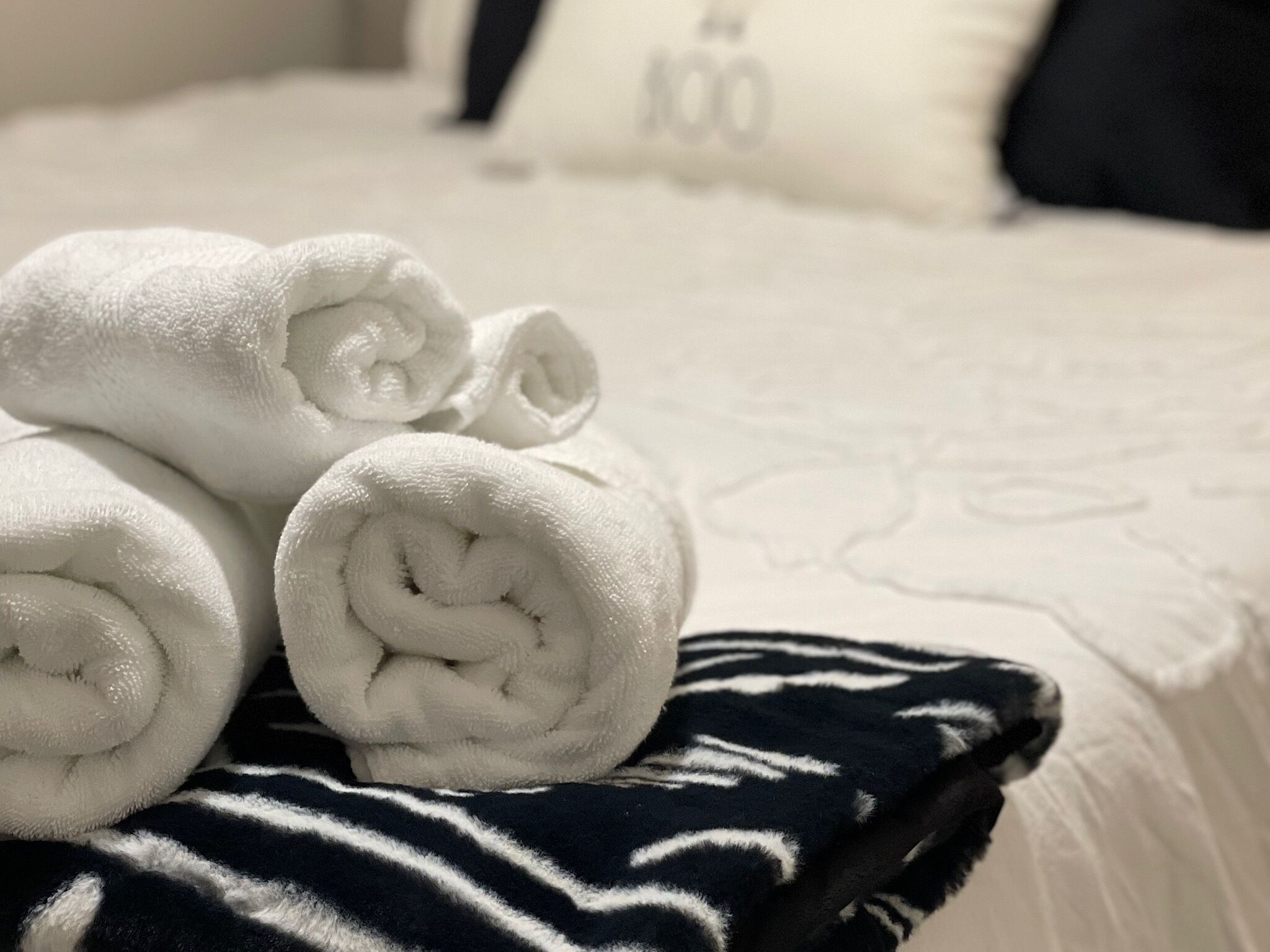 A neatly made bed with white towels and a striped blanket.