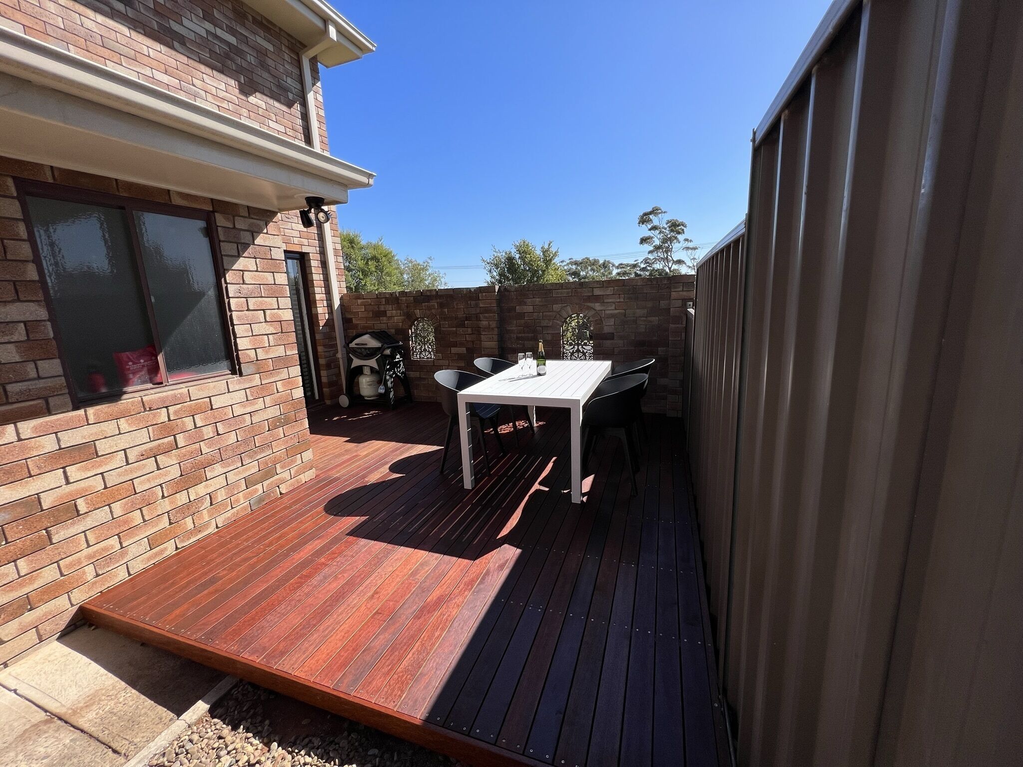 Une terrasse avec une plateforme en bois, une table blanche et des chaises.