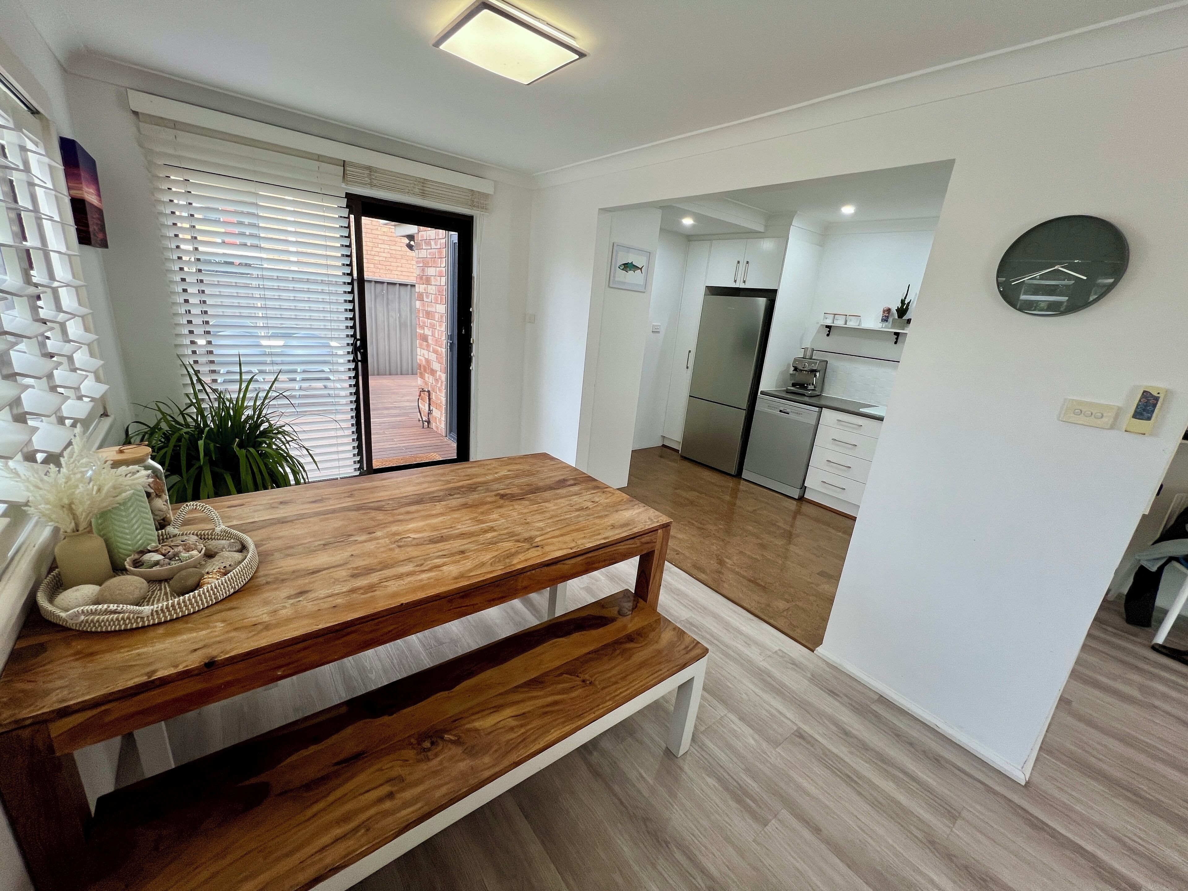 A modern kitchen with white cabinets, a stainless steel refrigerator, and a built-in oven.