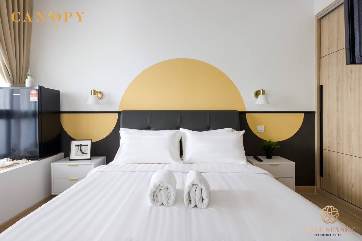 Een hotelkamer met een bed, twee nachtkastjes, een wandtelevisie en een groot rond ontwerp aan de muur.