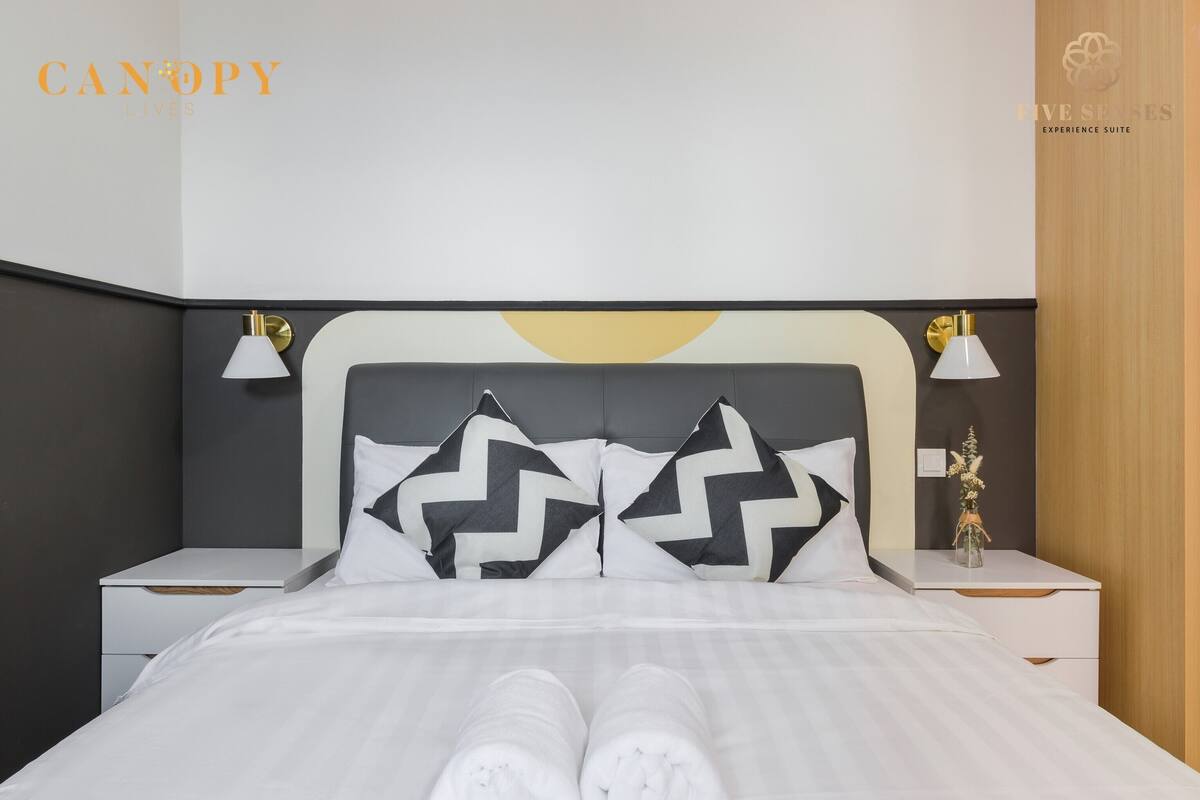 Een moderne hotelkamer met een bed, twee nachtkastjes en een bedlampje.