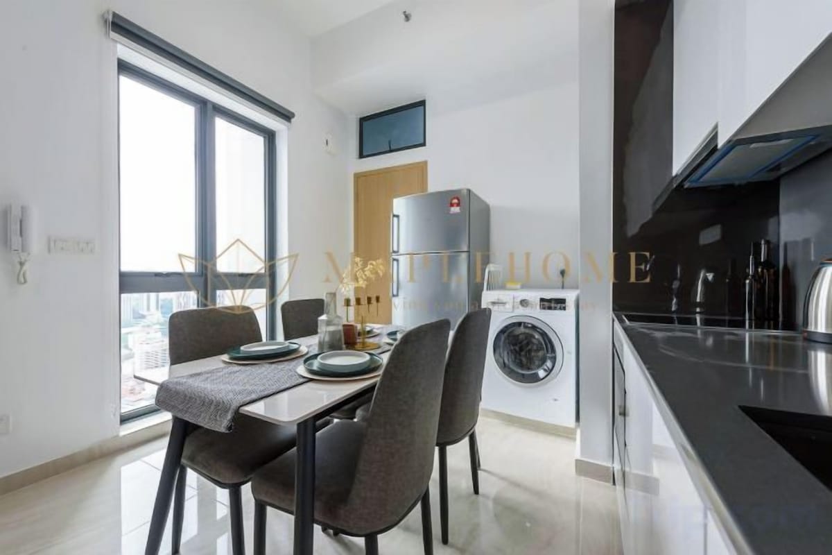Una cucina moderna con lavatrice, zona pranzo con tavolo e sedie, e un'ampia finestra che offre luce naturale.