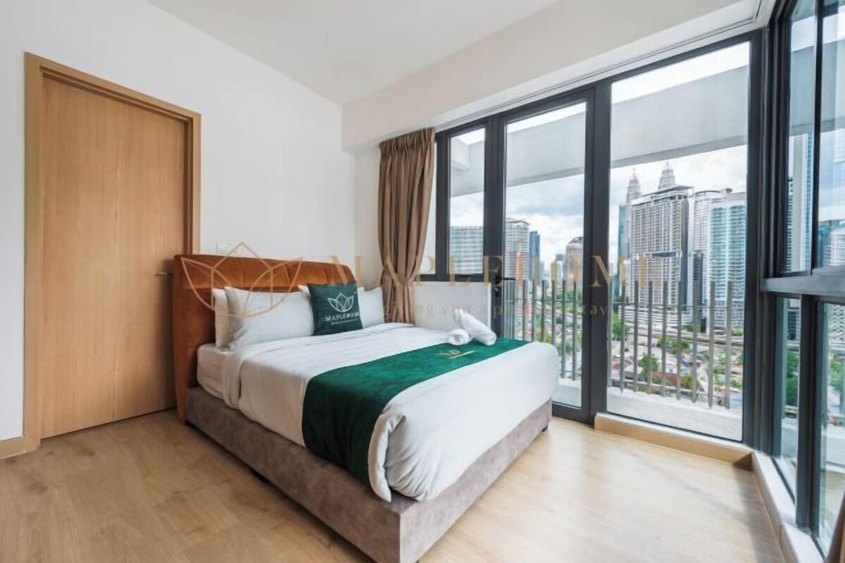 A modern hotel room with a large bed, a view of the city through floor-to-ceiling windows, and a balcony with a railing.