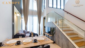 Een moderne eethoek met een houten tafel voor twee personen, een bank en een trap met glazen balustrades.