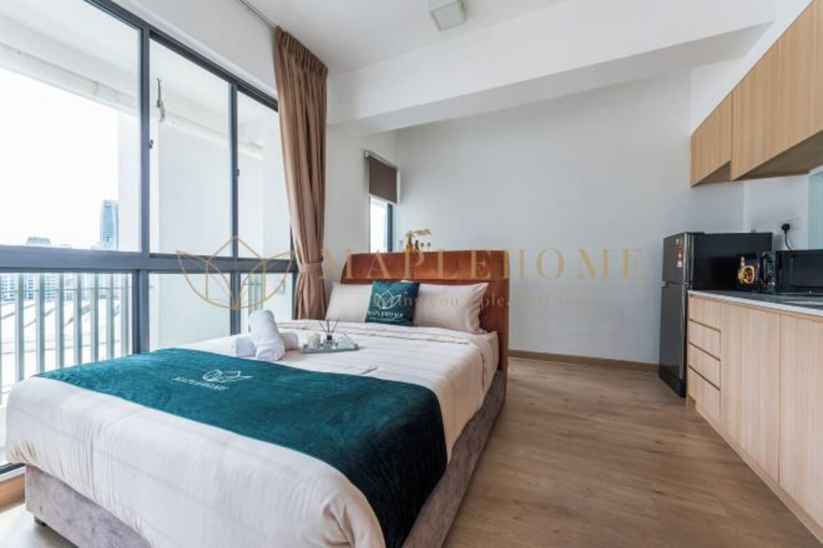 A modern bedroom with a large bed, a view of the city, and a kitchenette.