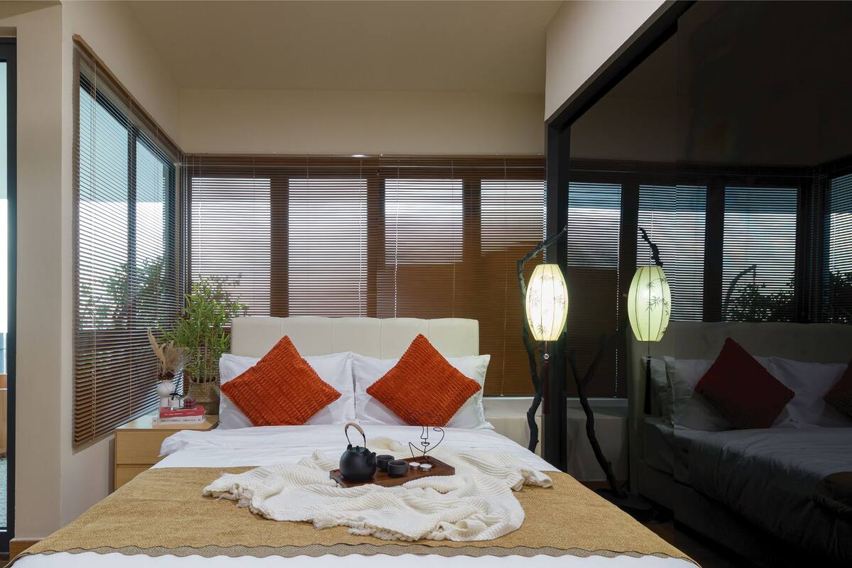 Een moderne slaapkamer met een bed, een nachtkastje met een plant en uitzicht op een balkon.