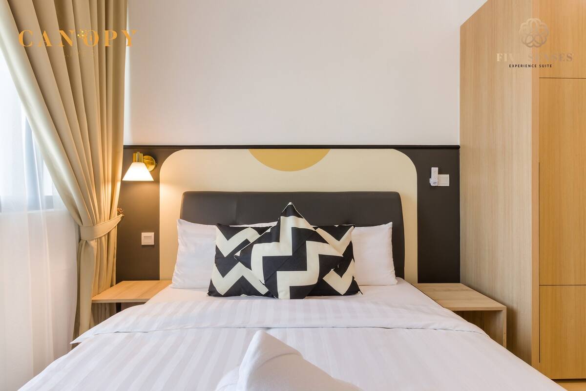 Een hotelkamer met een bed, nachtkastje, lamp en kledingkast.