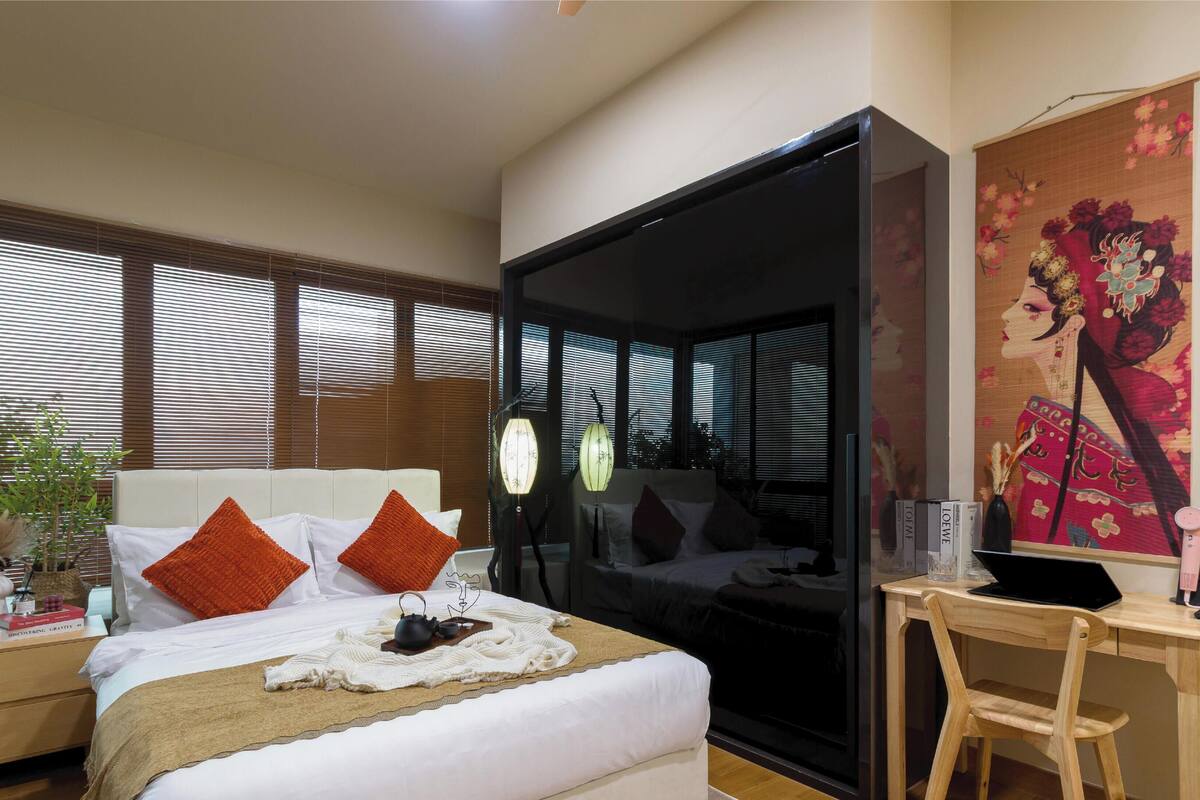 Een slaapkamer met een bed, een bureau en een groot raam met zonwering.