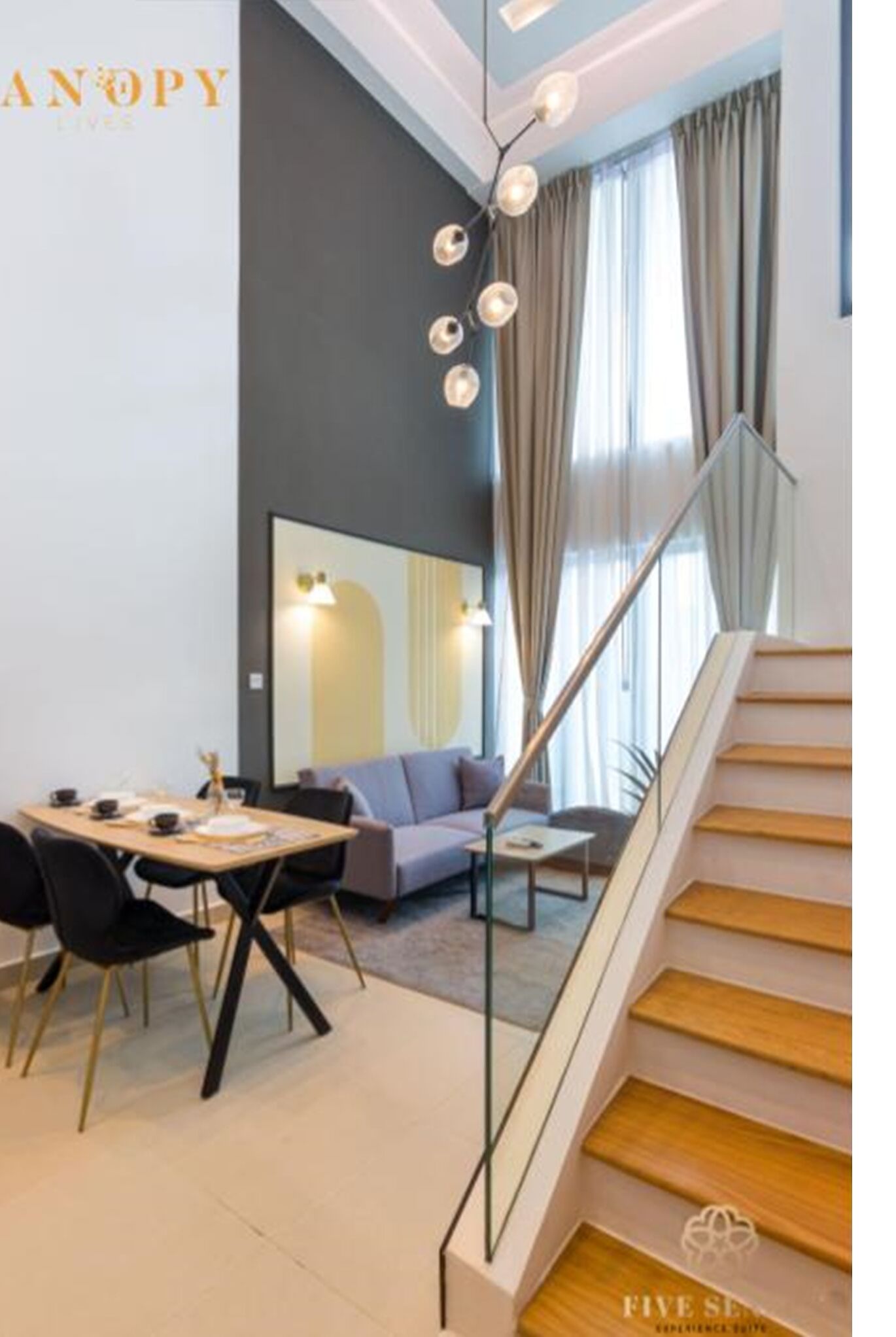 A modern living space with a dining area, a staircase, and a large mirror reflecting the room.