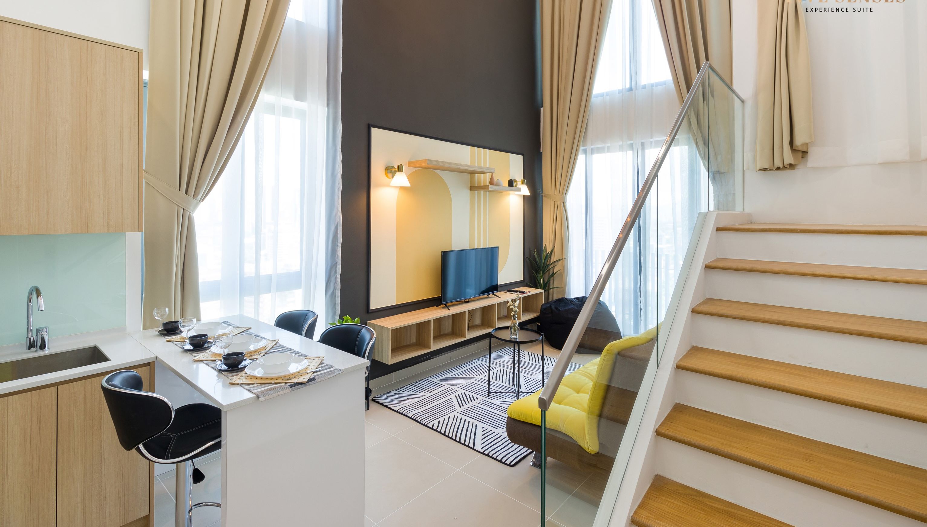 A modern living area with a kitchen, dining table, and a staircase.