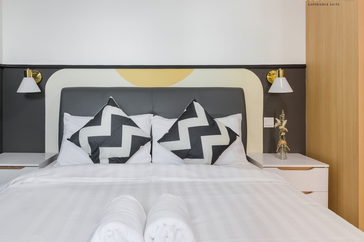 A modern hotel room with a bed, two nightstands, and a night lamp.