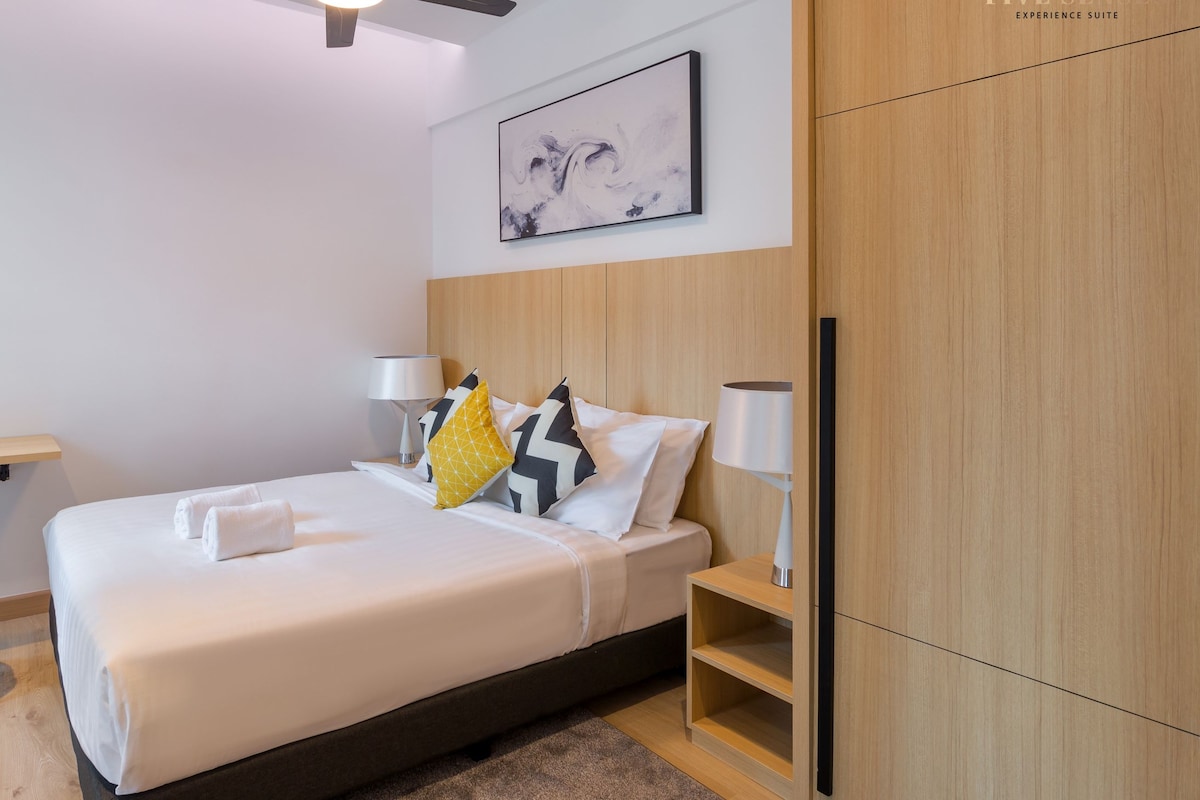 A modern hotel room with a bed, a desk, a chair, a ceiling fan, and a wardrobe.