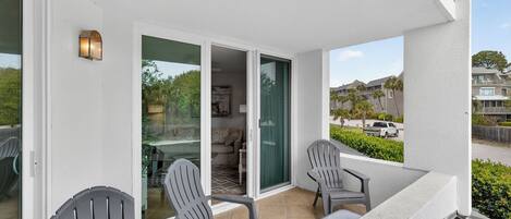 A balcony with chairs, a sliding glass door, and a view of a residential area.
