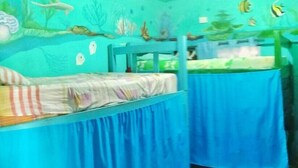 A room with two beds covered in blue sheets, a tiled floor, and a wall decorated with marine life illustrations. - Vampayá Panamá (Bocas del Toro)