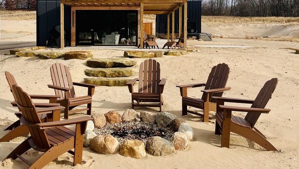 A modern house with a large open porch, a fire pit, and several Adirondack chairs. - Family Friendly Lake Front New Build - 5bdrm + Hot Tub (Stevensville)