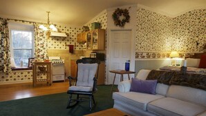 A cozy living room with a fireplace, a dining table, and a sofa. - Private Cottage “Wild Rose” (Julian)